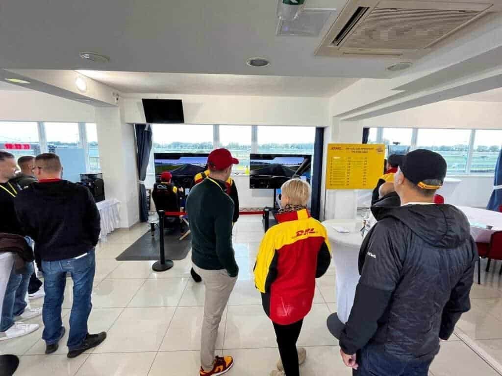 Multiple connected racing simulators for rent at the racing track paddock creating excitement at a large corporate event.