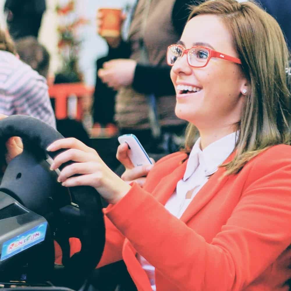Happy girl in red dress in a racing simulator in Austria, Vienna rented race car simulator.
