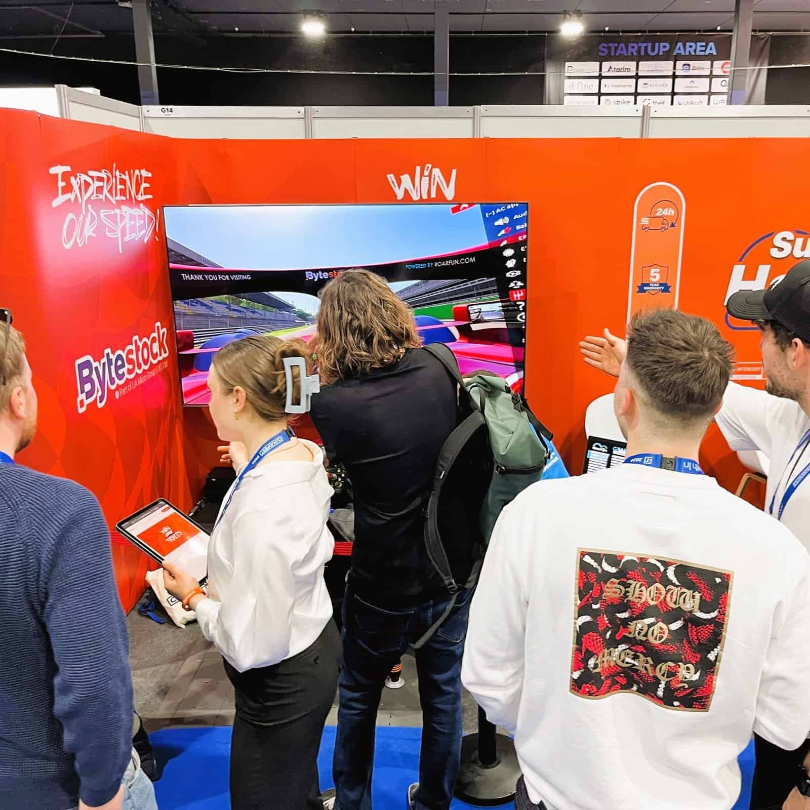 A big crowd around a F1 licensed seat motion simulator to generate leads in effective at a CloudFest lots of people.