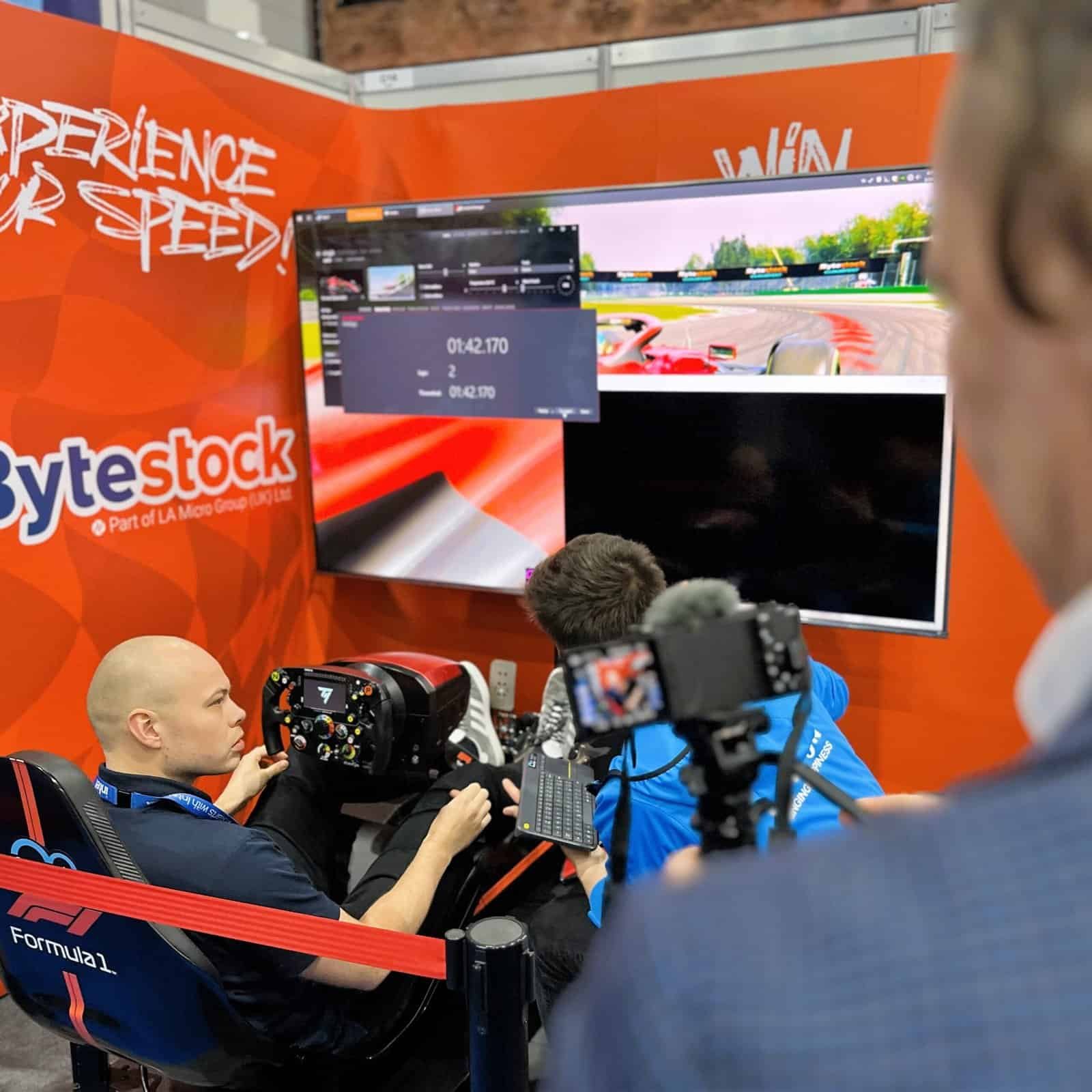 Man takes instructions for driving a Formula simulator at a cloudfest event.